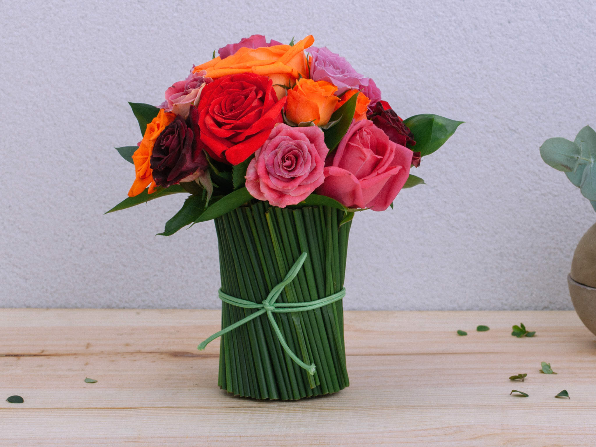 Arranjo de Rosas Coloridas em Vaso de Vidro Revestido com Junco